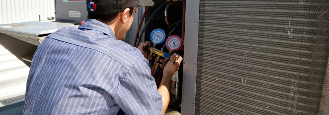 HVAC technician servicing a condenser unit in Putnam